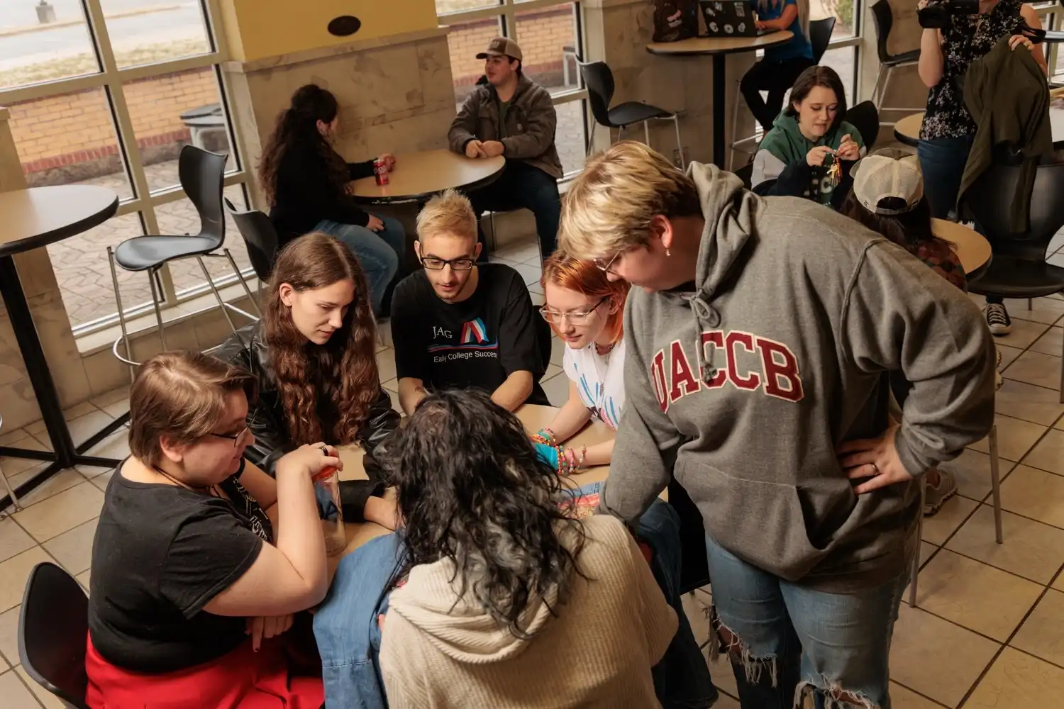 A group of UACCB students huddle around a table in the student union, engaged in a collaborative activity.